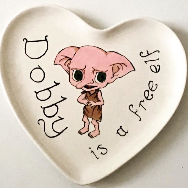 Dobby, a small creature, stands in a heart frame.