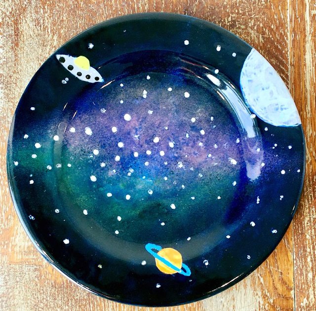 A dark blue plate with painted planets and stars.