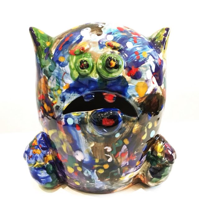 Colorful ceramic monster head with green eyes.