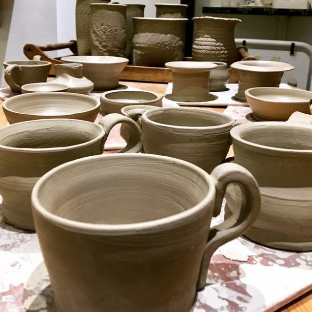 Close-up of unglazed clay mugs and pottery on a workbench.