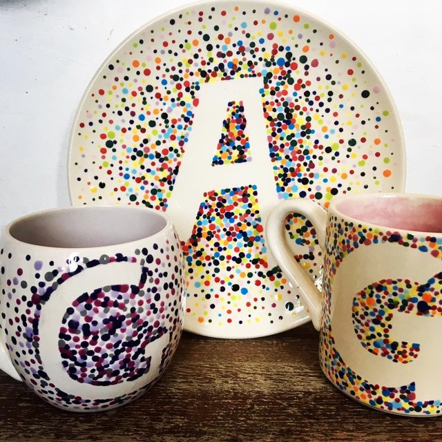 Colorful ceramic mugs and plate with a dot pattern.