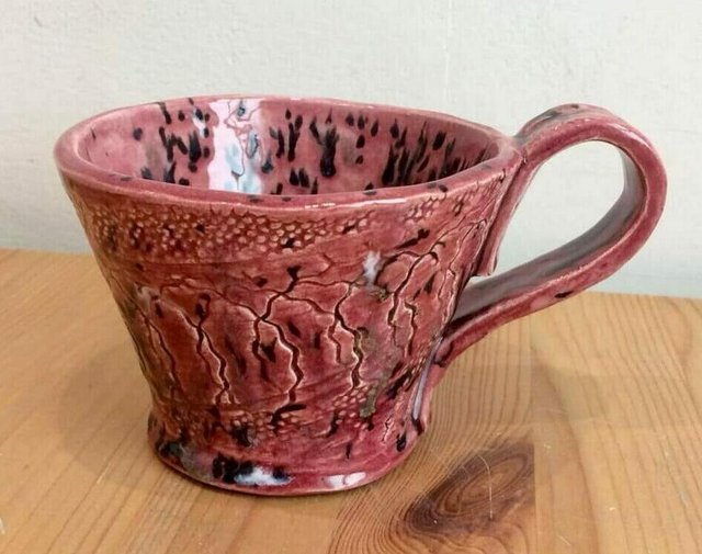Pink and black ceramic mug with a textured surface.
